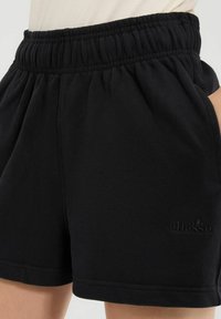 Pantalones cortos de sudor negros con cinturilla elástica y bolsillos laterales. Tela suave, corte relajado, con un logotipo sutil en el bajo.