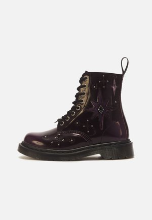 Bottine montante à lacets violet foncé brillant avec semelle noire, décorations étoiles et petits clous, et une languette à l’arrière.