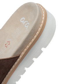 Sandale mule en cuir marron avec une semelle intérieure beige douce, une semelle extérieure blanche texturée, et un détail de couture contrastante le long du bord.