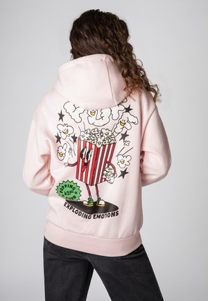 Roze hoodie met een cartoon popcorn personage dat in een gestreepte verpakking zit, omringd door lachende popcorn en sterren.