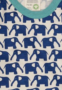 Blaues Elefantenmuster auf einem cremefarbenen Hintergrund mit einem türkisfarbenen, gerippten Halsausschnitt. Aus Bio-Baumwolle gefertigt und mit verspielten, einfachen Designs versehen.