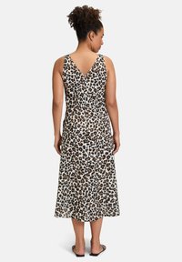 Kleid im Leopardenmuster mit V-Ausschnitt, ärmellosem Design und Länge bis zur Mitte der Waden. Hergestellt aus einem leichten Stoff mit glatter Textur.