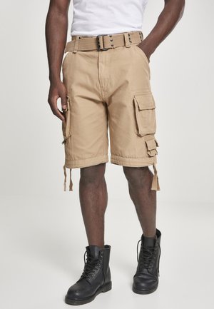 Tan cargo shorts med flere lommer, justerbar midje og snoretrekksdetaljer. Brukt med svarte snørebåndsstøvler.