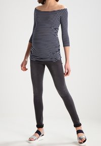 Stilltop mit navyblauen und weißen horizontalen Streifen, schulterfrei; kombiniert mit dunkelgrauen Skinny Jeans und schwarzen und silbernen Sandalen.