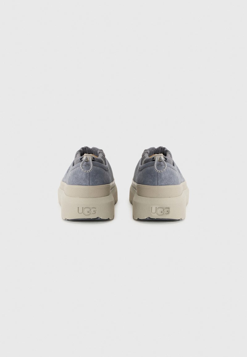 Chaussures décontractées en daim gris avec une semelle plateforme beige, dotées d'ouvertures élastiquées et d'un logo discret au talon.