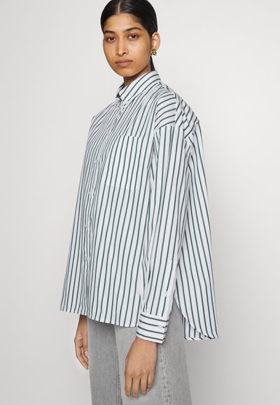 Camicia a righe bianca e verde, con colletto a punta, taschino sul petto e maniche morbide. Tessuto strutturato e design informale.
