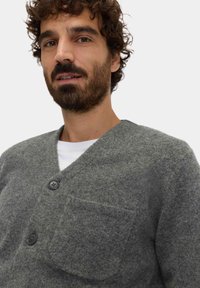 Grau gestrickte Wolle-Kardigan mit V-Ausschnitt, zwei schwarzen Knöpfen und einer aufgesetzten Tasche auf der linken Seite. Weiche Textur mit lässigem Schnitt.