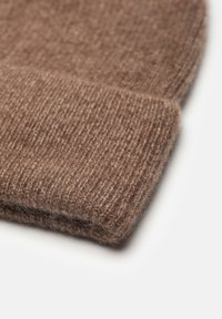 Brązowa dziana czapka beanie o prążkowanej fakturze. Posiada podwinięty mankiet, wykonana z miękkiego materiału wełnianego, zapewniająca ciepło i komfort.