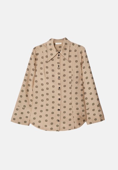 Camisa bege de botão com mangas longas, apresentando um padrão floral repetido em verde escuro, com colarinho pontudo e fecho frontal por botões.