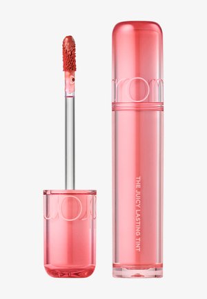 Lippenfarbe in einem transparenten, pinkfarbenen zylindrischen Behälter mit Applikatorpinsel, auf dem das korallenrote Produkt zu sehen ist.