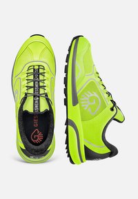 Neon-gelbe Sportschuhe mit strukturiertem Design, schwarzer Laufsohle, reflektierenden Akzenten sowie einem Logo an der Seite und Zunge.