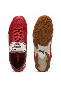 Crvene kožne nogometne cipele s bijelim jezikom, crnim detaljima, gumenim potplatom i teksturiranim gaznim slojem. Sadrže "Puma KING" oznaku na jeziku.