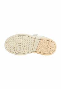 Suola di scarpa con un design testurizzato; materiale in gomma di colore bianco sporco. Presenta un accento con logo circolare e grip a fantasia per una migliore aderenza.