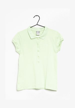 Jasnozielona koszulka polo Nike z krótkimi rękawami, zapinana na guziki, z małym białym logo Swoosh na lewej piersi, wisząca na czarnym wieszaku.