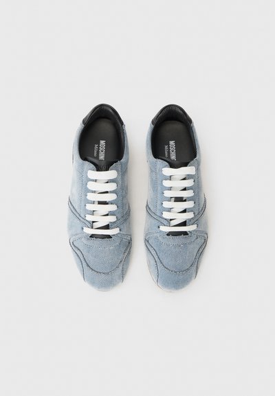 Denim sneakers with light blue material, featuring white laces, black accents at the collar, and a textured surface.