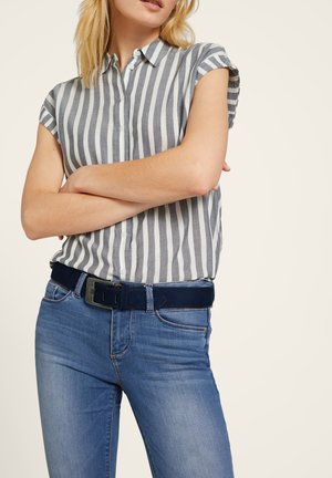 Kurzärmliges, khakifarbenes Hemd mit blauen und weißen vertikalen Streifen, kombiniert mit blauen Jeans und einem dunkelblauen Gürtel mit einer silbernen Schnalle.