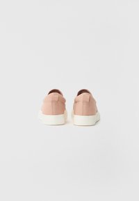 Rosa kanvas joggesko med en glatt tekstur, med såle og hæltab i hvitt; minimalistisk design med stitched aksenter.