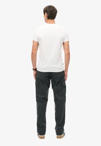 Witte korte mouwen T-shirt in combinatie met donkergrijze cargobroek met zijzakken, rechte pasvorm en een zachte stoftextuur.