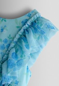 Hellblauer, floraler Netzstoff mit gerafften Details an der Schulter und dunkelblauen sowie grünen Blumenmustern auf dem gesamten Stoff.