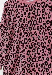 Camisa de manga larga en rosa con un patrón de leopardo negro. Tejido suave con un escote redondo y corte holgado.