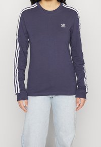 Námořnické tričko s dlouhým rukávem vyrobené z bavlny, zdobené bílým designem se třemi pruhy na rukávech a malým bílým logem na hrudi.