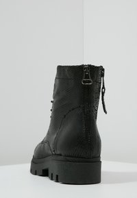 Czarne botki do kostki z teksturowanym materiałem przypominającym skórę węża. Posiadają boczny zamek, sznurowany fason i grubą gumową podeszwę.