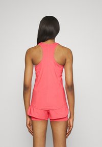 Roze sporttanktop met een racerback-ontwerp, gemaakt van zachte stof, gecombineerd met bijpassende shorts met een elastische tailleband en een losse fit.
