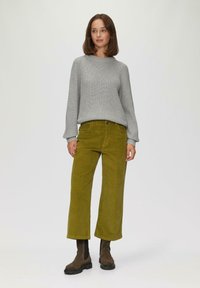Grijze gebreide trui, olijfgroene corduroy wijde broek en bruine enkellaarsjes, met zijzakken en een losse pasvorm.
