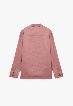 Chemise à manches longues en rose poussiéreux, fabriquée en tissu léger. Elle possède un col, des poignets à boutons et un ourlet droit avec un empiècement au dos.