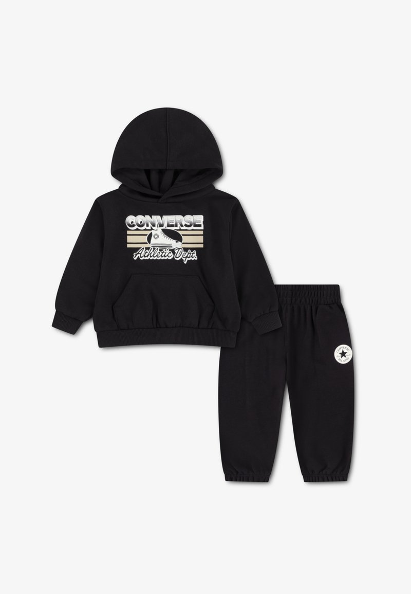 Ensemble sweat à capuche et pantalon de survêtement noir en matière douce, comprenant une poche avant, des poignets côtelés et un patch logo sur le pantalon.