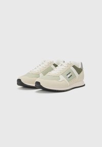 Sneakers beige e verde chiaro caratterizzati da un mix di materiali in suede e rete, con accenti laterali a motivo e una suola in gomma nera.