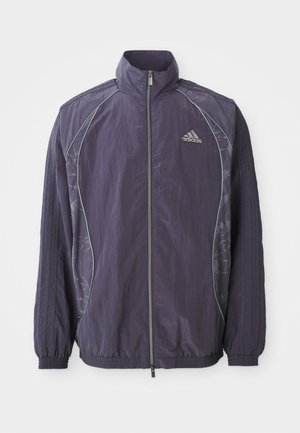 Paarse Adidas zip-up sportjack met hoge kraag, elastische manchetten en zoom, reflecterende bies en subtiele bloemmotieven aan de zijkanten.
