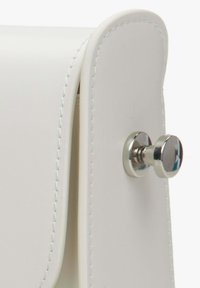 Bílá kabelka z faux kůže s hladkým povrchem, s kovovým zacvakáváním a čistým prošíváním podél okrajů.