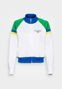Bílá zipová bunda s ramenními panely v zelené, modré a žluté barvě, modrým límcem a lemem, a logem Polo Sport Ralph Lauren s vlajkou na hrudi.