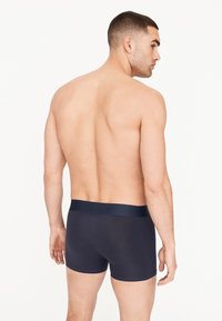 Marineblaue Baumwollboxershorts mit einem glatten Bund. Die Passform ist eng und der Stoff wirkt weich mit einem leichten Glanz.