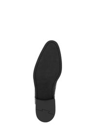Suela de zapato de cuero negro con una textura suave. Presenta una forma ligeramente puntiaguda, borde acolchado y detalle de logo en relieve en la zona del talón.