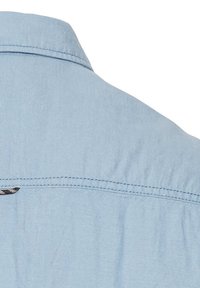 Lichtblauw chambray overhemd met een puntkraag, subtiele textuur en een klein logo-accent op de rughals.