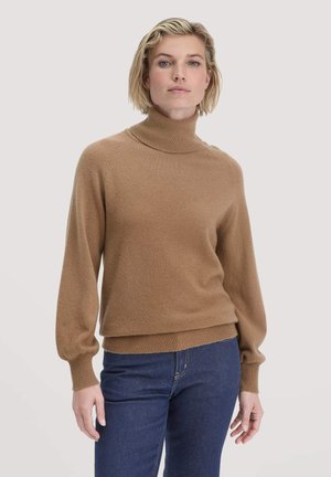 Brauner Rollkragenpullover mit Ballonärmeln, gerippten Bündchen und Saum. Weicher Griff und lockere Passform, kombiniert mit dunklen Jeans.