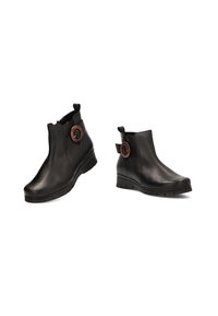 Botas negras hasta el tobillo hechas de cuero suave, con un tacón de cuña, punta redondeada y un acento circular de madera en el costado.