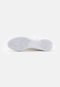 Suela de zapatilla atlética blanca con goma texturizada, que presenta un diseño ondulado y patrones de tracción para agarre y estabilidad.