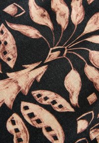 Tissu noir avec des motifs floraux et feuilles abstraits beiges, présentant des découpes en forme de losange et des lignes ondulées ressemblant à des tiges de plantes.