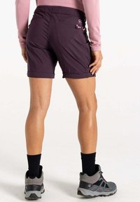 Pantalones cortos morados con dobladillos enrollados, con ajustes laterales y una textura suave, combinados con zapatos de senderismo grises y calcetines negros.