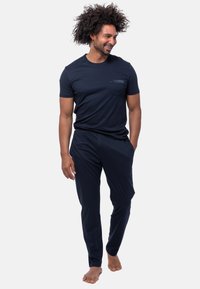 Mörkblå bomullspyjamas set som inkluderar en kortärmad skjorta med ficka och matchande tapered byxor, slät textur, avslappnad passform.