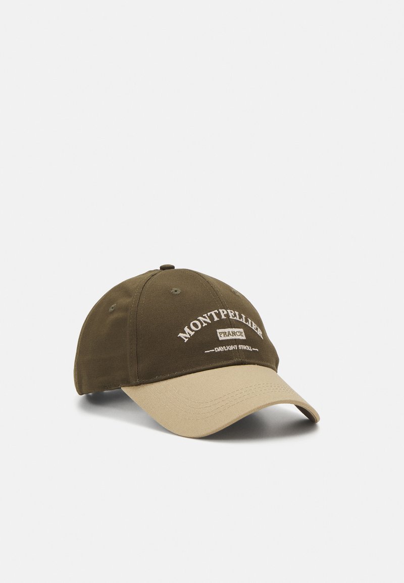 Brown and beige cap with stitched "Montpellier France" text. Features a curved brim and adjustable back, made from textured fabric.