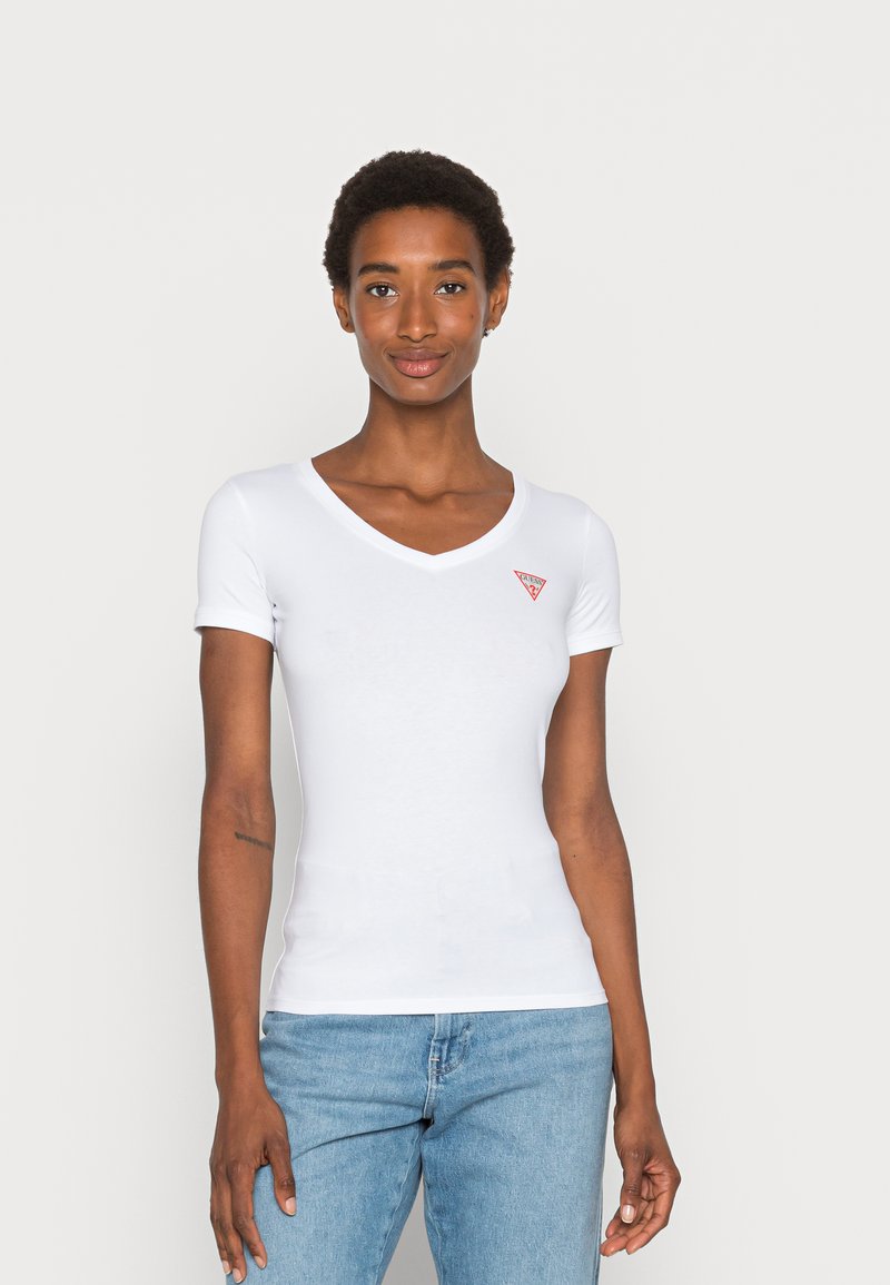 Camiseta blanca de manga corta con cuello en V, hecha de una tela suave, que presenta un pequeño logotipo triangular rojo en el lado izquierdo del pecho y un diseño ajustado.