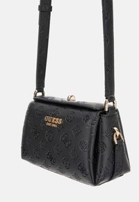 Borsa nera con motivi in rilievo, logo dorato "GUESS EST 1981", design strutturato e tracolla removibile. Materiale in pelle texturizzata.