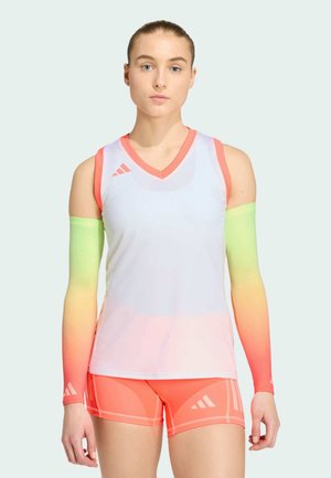 Młoda kobieta ubrana w biały bezrękawnik sportowy, koralowe szorty oraz gradientowe rękawy od neonowo zielonego do koralowego, zwrócona przodem na prostym tle.
