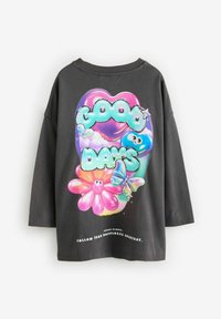 Svart oversized t-shirt med en färgglad grafik av stiliserad text, blommor och en fjäril. Mjuk bomullsmaterial, avslappnad passform.