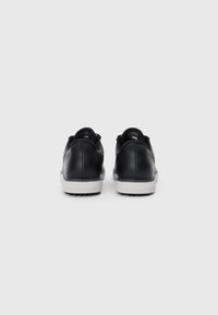 Baskets en cuir noir avec une texture lisse, dotées d'une semelle en caoutchouc blanche, d'une forme arrondie et d'un col rembourré pour le confort.