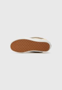 Tan and white sneaker sole with a textured rubber bottom. Features a geometric pattern on the rubber and a smooth white edge.